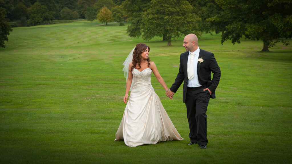 Newlyweds walking through the manicured gardens at Rudding Park, captured by Howard Barnett Photography.