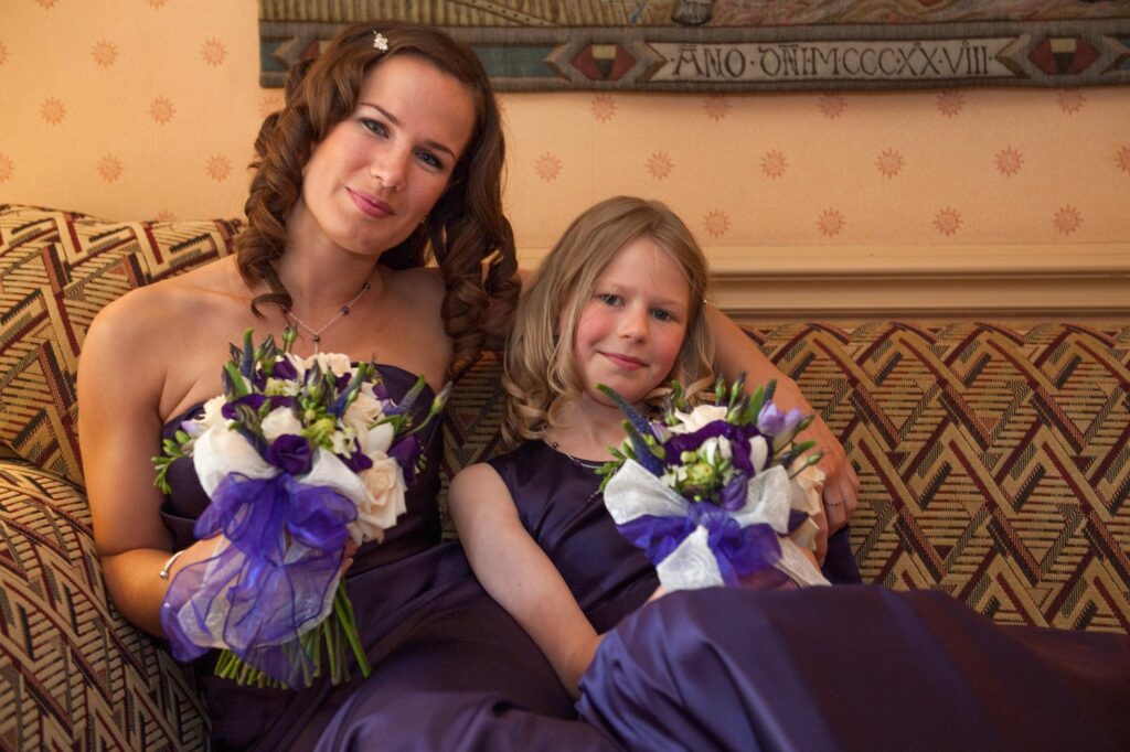 Two bridesmaids in elegant purple dresses holding bouquets at a Weetwood Hall wedding in Leeds.
