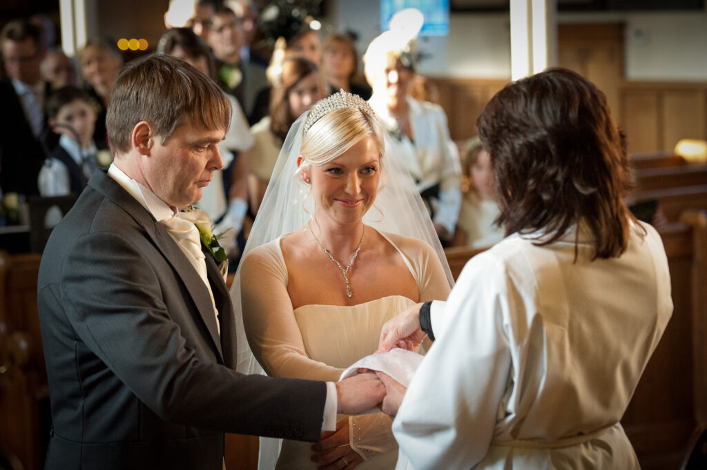 Close-up of a bride and groom holding hands during their wedding ceremony at Christ Church Harrogate.