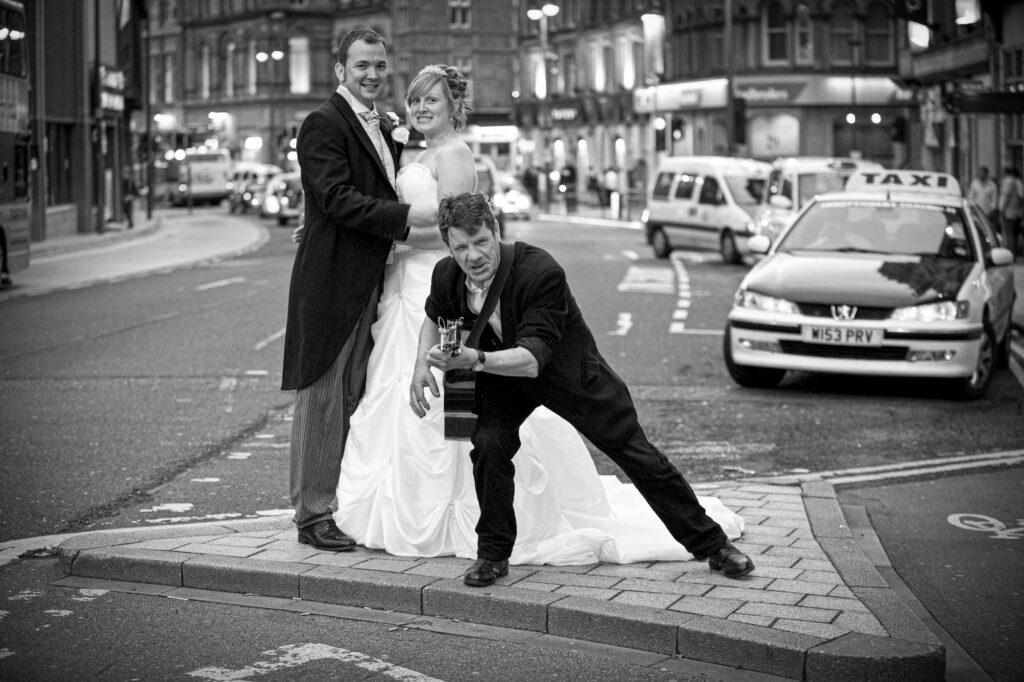 A fun, candid wedding moment in Leeds city center featuring a couple and a street guitarist, showcasing the unscripted joy of a city wedding.