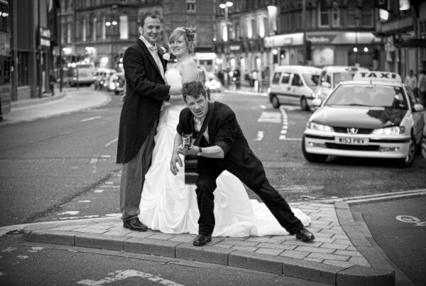A fun, candid wedding moment in Leeds city center featuring a couple and a street guitarist, showcasing the unscripted joy of a city wedding.