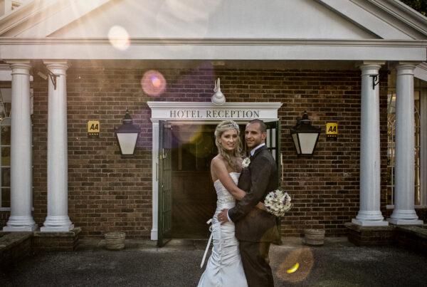 Bride and groom embracing in front of the "Hotel Reception" entrance at The Bridge Inn with sunset lens flare.