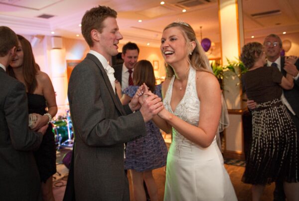 Newlyweds laughing and dancing during their wedding reception at Weetwood Hall, captured by Howard Barnett.