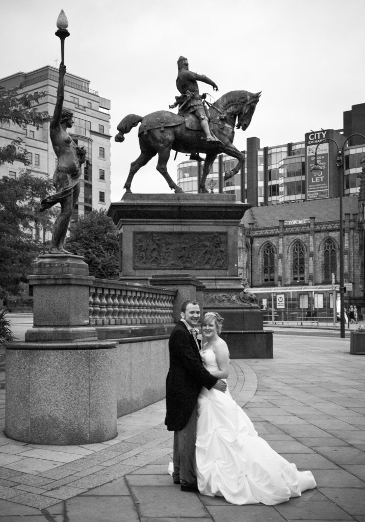 A fun, candid wedding moment in Leeds city center featuring a couple and a street performer, showcasing the "unscripted joy" style of Howard Barnett Photography.