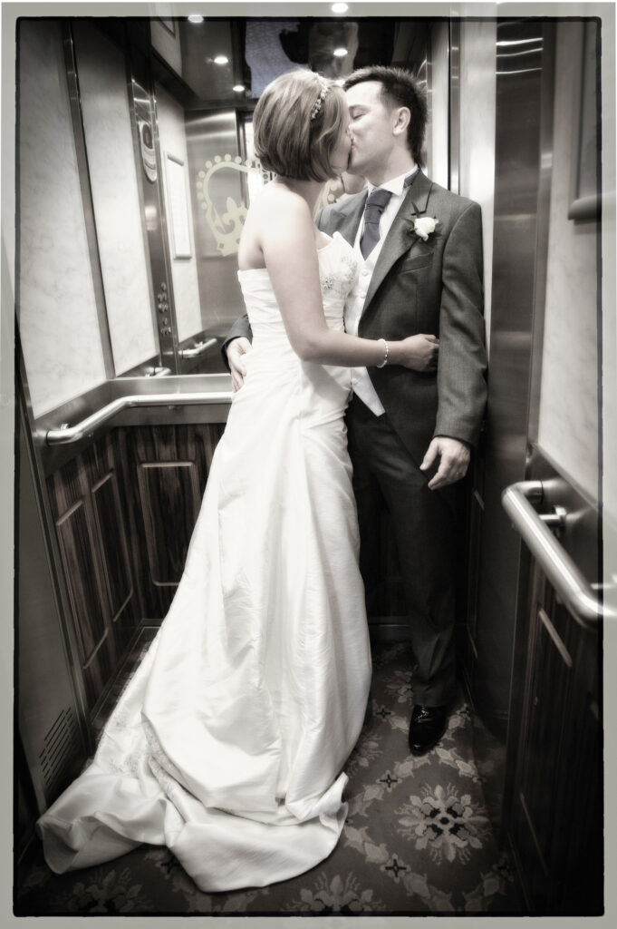 Black and white photograph of a bride and groom kissing inside the vintage elevator at The Crown Hotel, Harrogate.