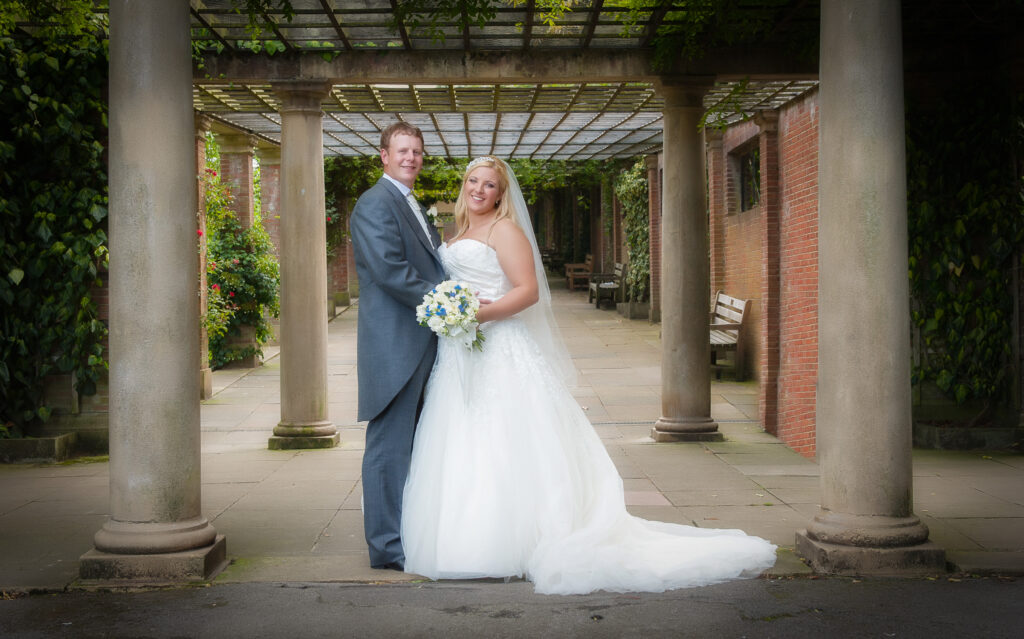 Professional wedding portrait of a couple under the historic stone pergola at Valley Gardens, Harrogate by Howard Barnett Photography.