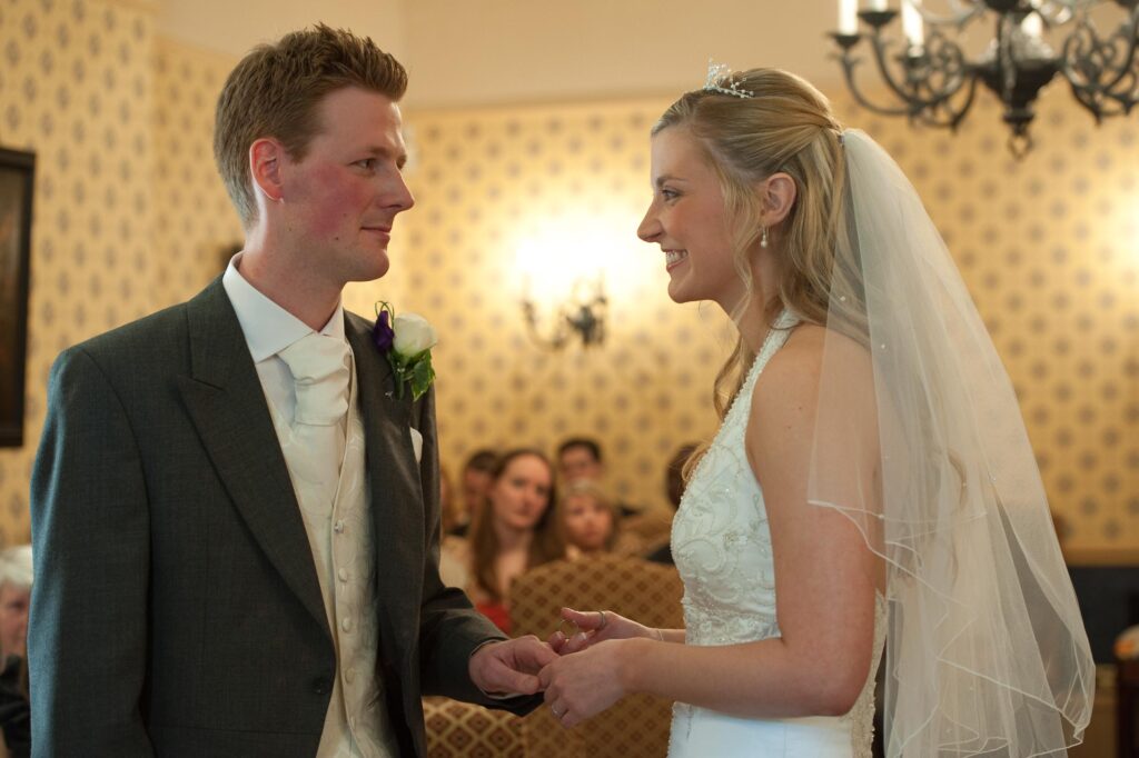 Close-up of a bride and groom exchanging rings during a wedding ceremony at Weetwood Hall, Leeds.