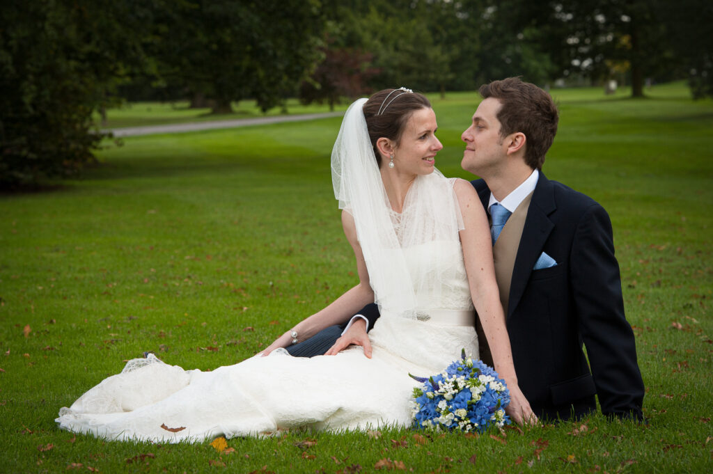 Wedding couple sitting together on the grass at Rudding Park Harrogate North Yorkshire by Howard Barnett Photography