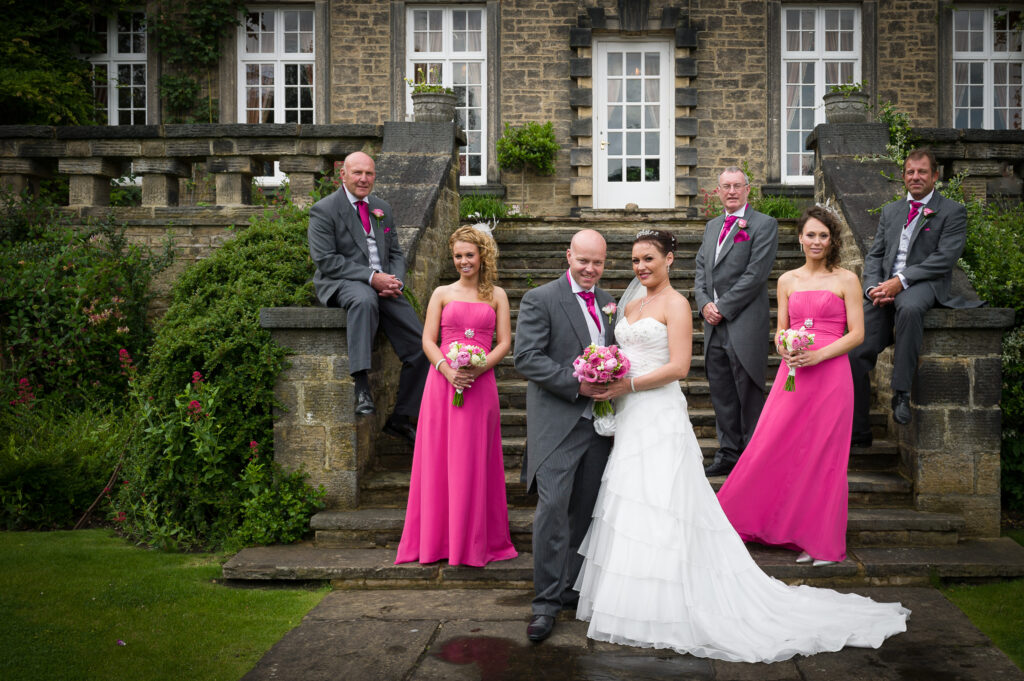 The full wedding party posing on stone steps of an Edwardian-Baroque style mansion in Baildon, West Yorkshire.