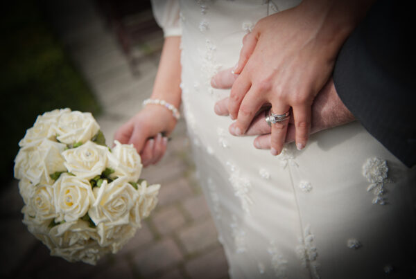 Close-up detail shot of wedding rings resting on a white rose bouquet by Howard Barnett Photography.