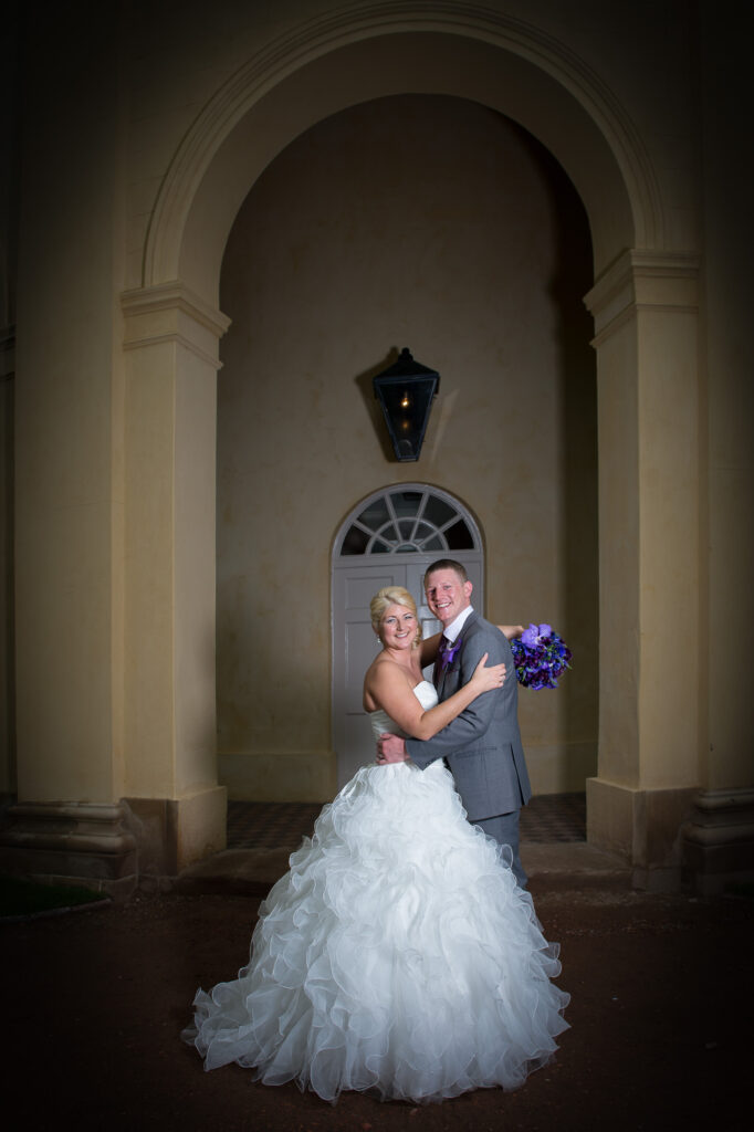 Bride and groom embracing under a large stone archway at a York wedding venue during an evening photo session.
