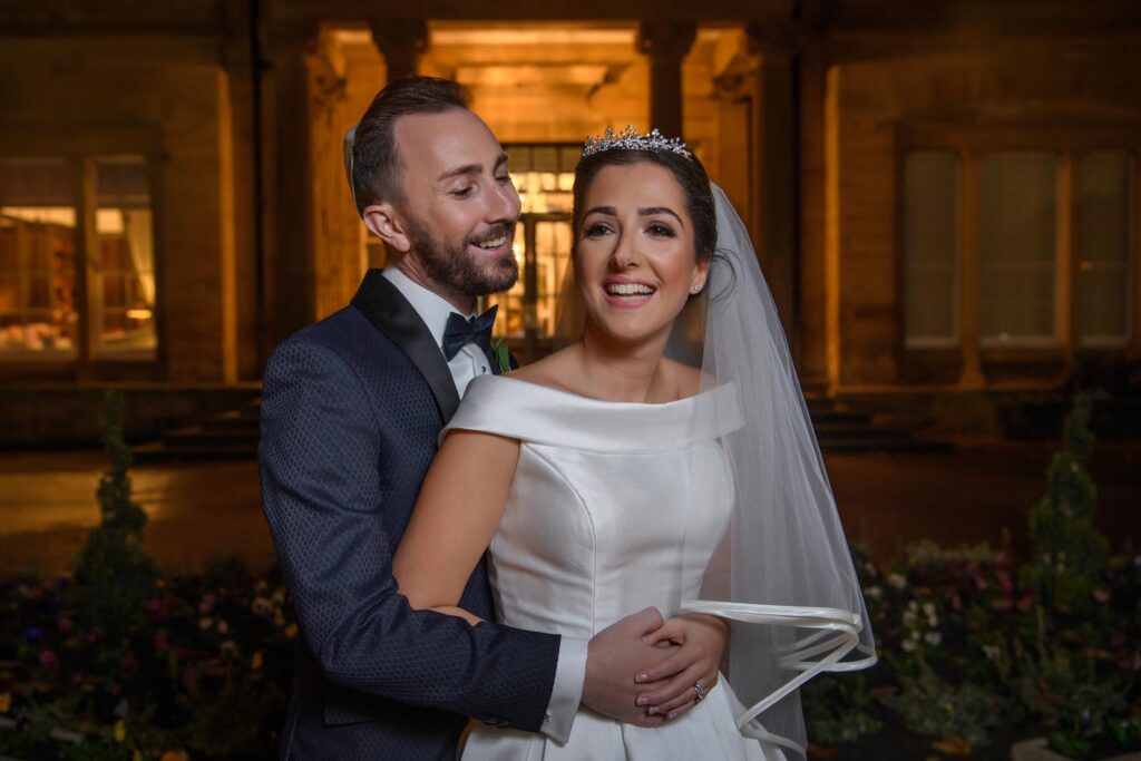 Documentary style wedding photography of a couple embracing at night outside a historic Leeds venue.