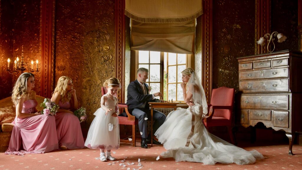 Bride and groom playing chess in a luxury wood-paneled room, captured by Howard Barnett Wedding Photography Leeds.