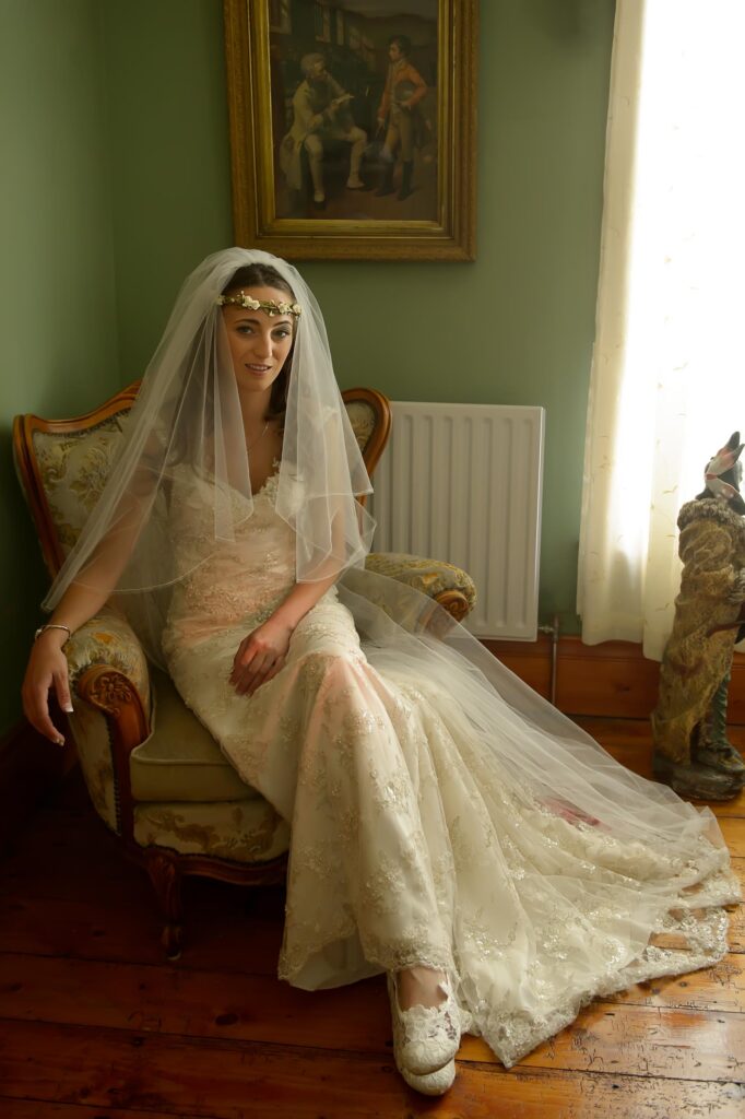 Close-up portrait of a bride wearing a floral crown and lace veil by a window, Harrogate wedding photography.