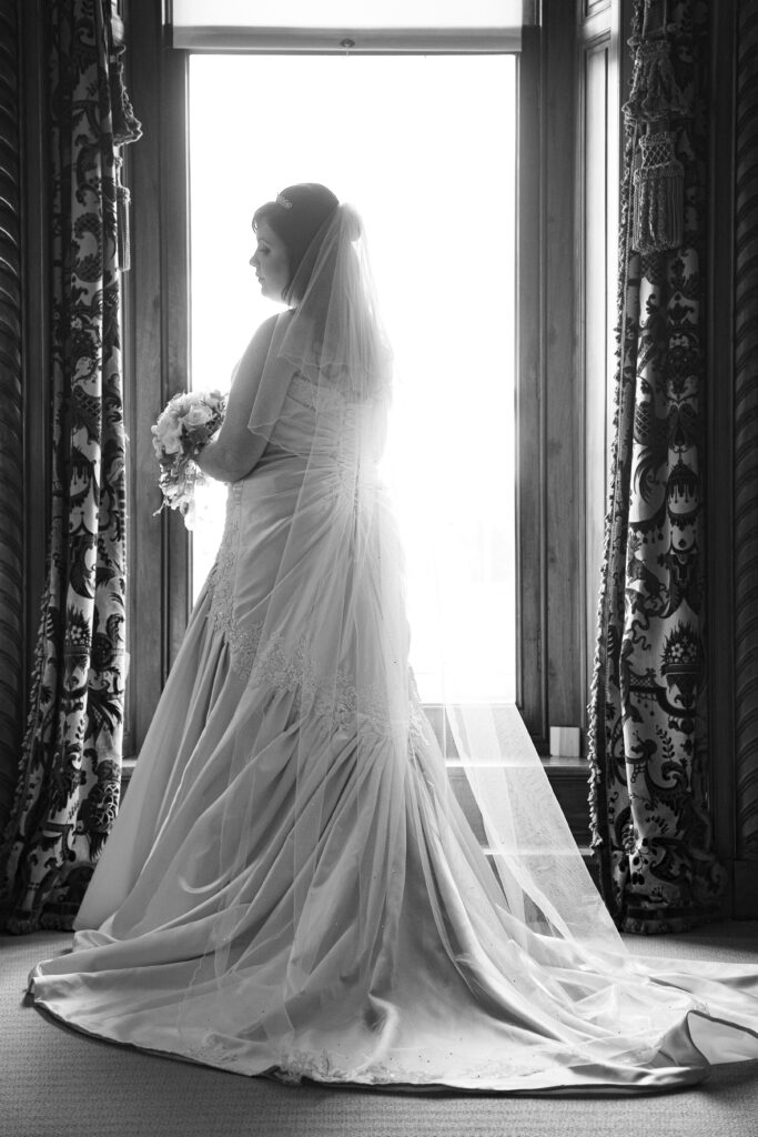 Silhouette-style bridal portrait by Howard Barnett showing the back of a wedding dress and long veil in Harrogate.