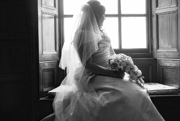 Elegant bridal portrait by Howard Barnett featuring a bride sitting by a large window at a Harrogate wedding venue.