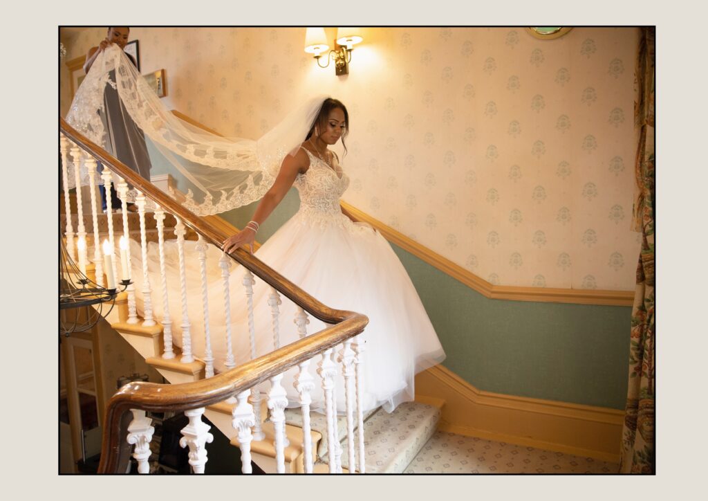 Bride Sophie descending the grand staircase at The Manor House, a highlight from the best wedding photographer in Leeds.