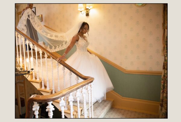 Bride Sophie descending the grand staircase at The Manor House, a highlight from the best wedding photographer in Leeds.
