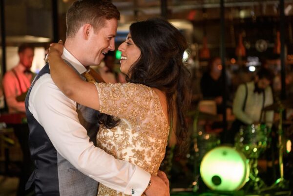 A bride and groom sharing an intimate first dance at a Leeds wedding venue, with a live band and green stage lighting in the background.