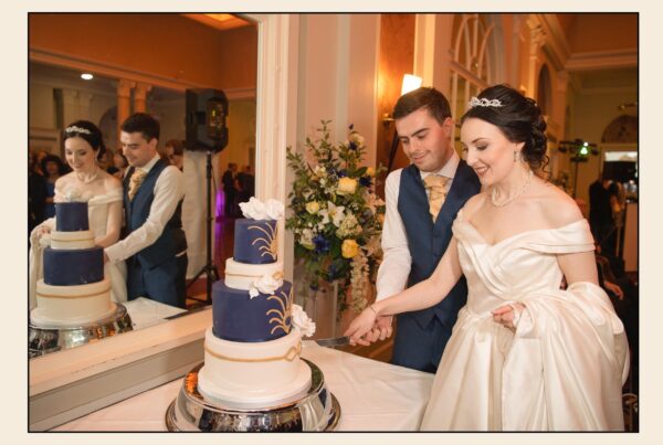 Bride and groom cutting a four-tier navy and white wedding cake during their reception at The Queens Hotel.